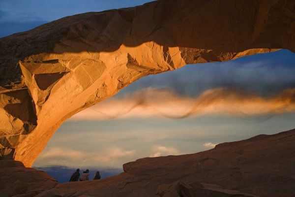 UT, Arches NP Hikers at Skyline arch at sunset